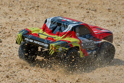 FMS FSC24 Chaser RC truck off-road action - red body powering through deep sand, tires spinning and spraying sand.