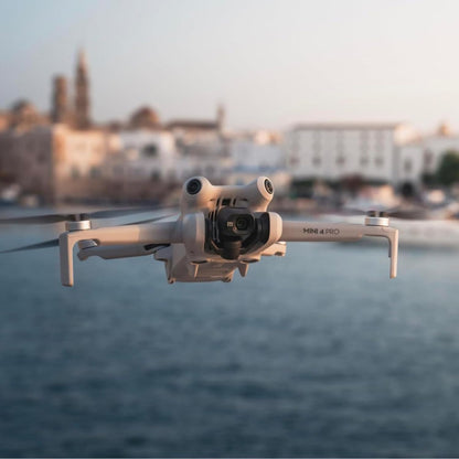 DJI Mini 4 Pro Fly More Combo, drone flying over waterfront with buildings in background, 135 g ultralight design, 4K HDR camera, 3-axis gimbal