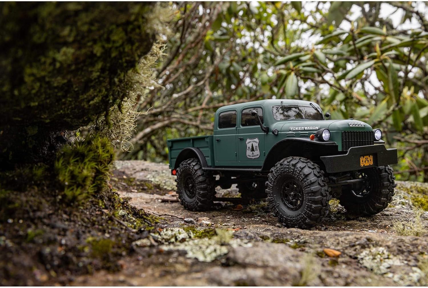 Green off-road Axial 1/24 crawler on a forest path