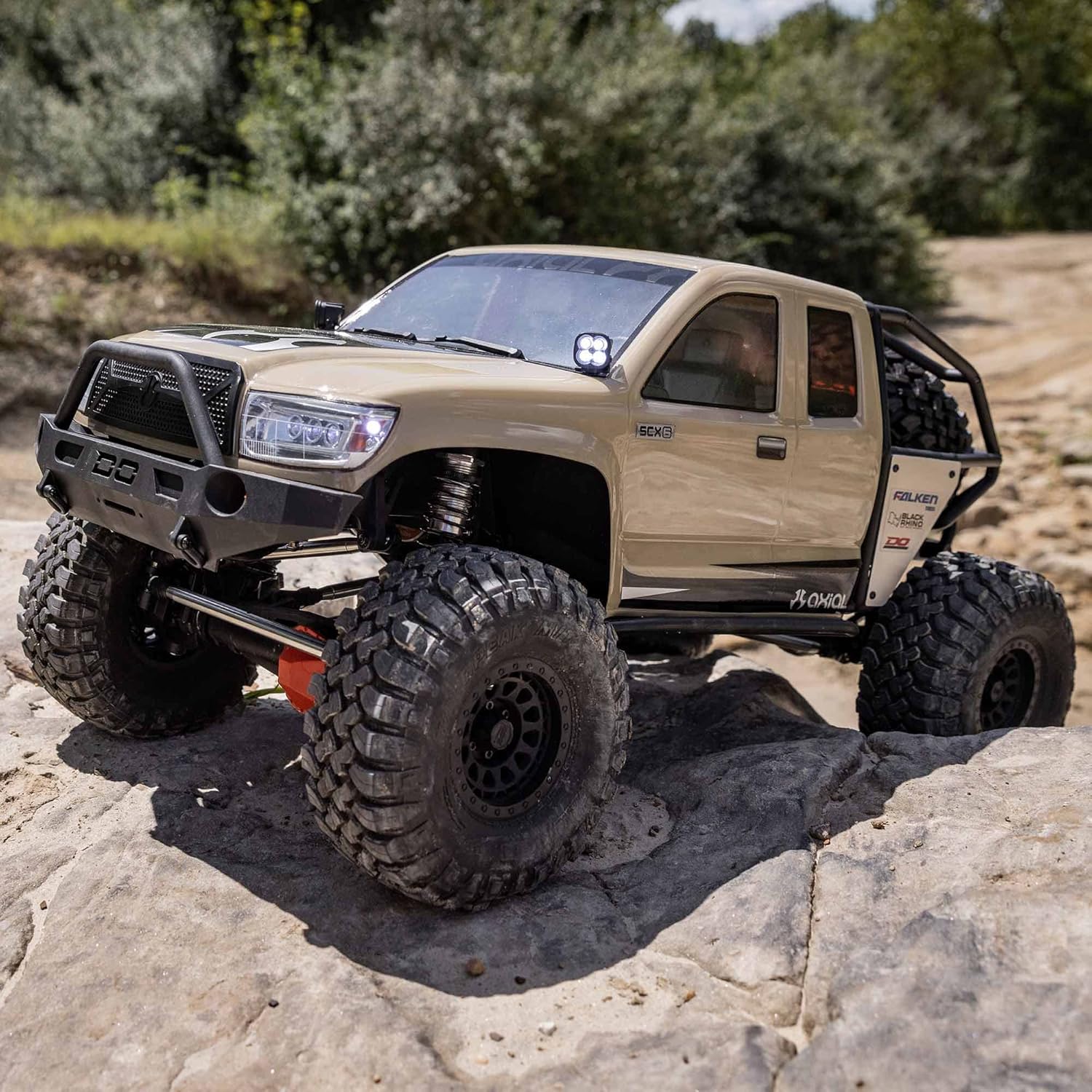 Axial SCX6 Trail Honcho 1/6 RTR rock crawler in action, climbing rugged terrain, blue body with suspension articulation, massive tires gripping rocks