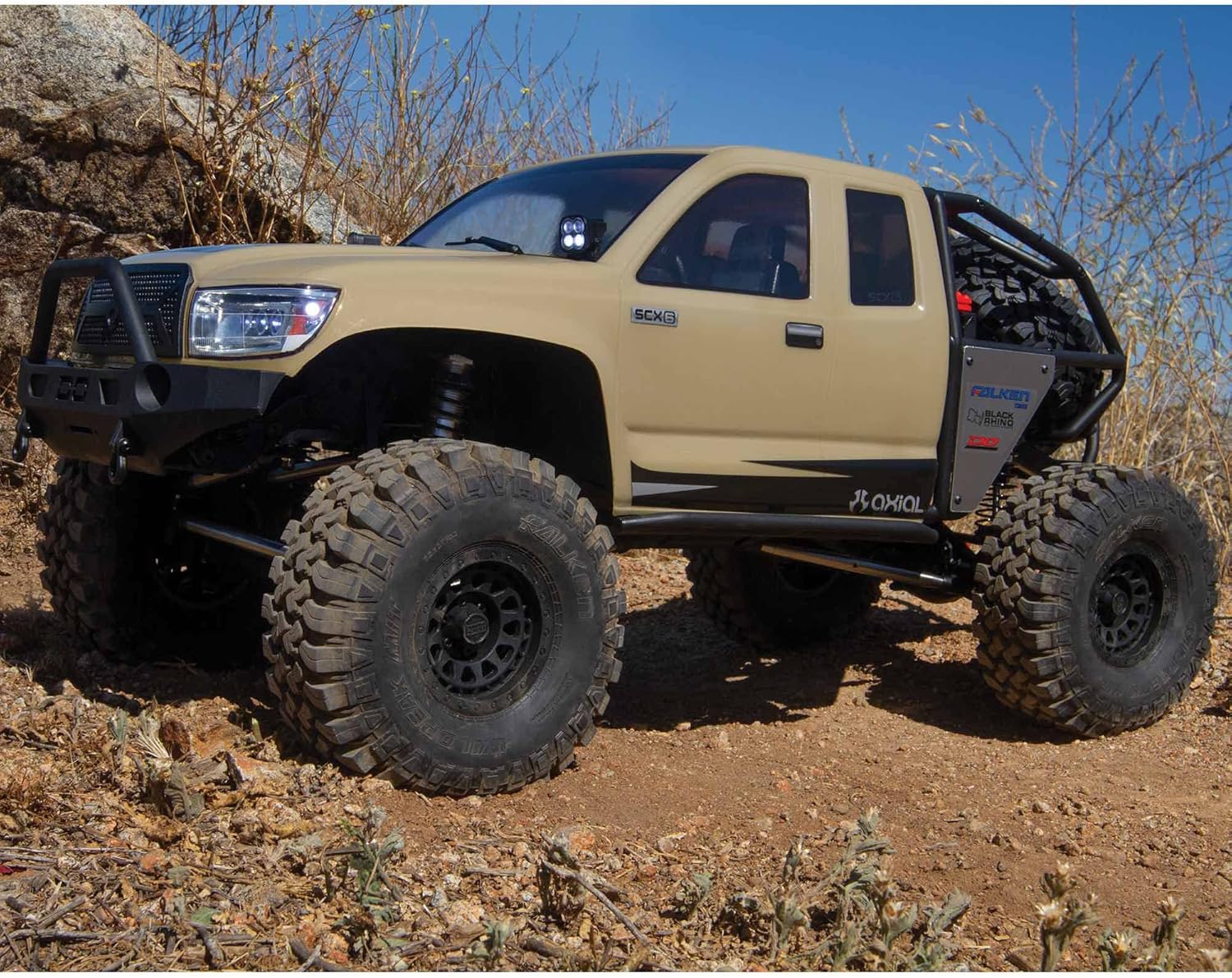 Beige off-road Axial SCX6 Trail Honcho 1/6 scale rock crawler with large tires on a rocky terrain