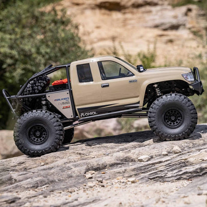 1/6 scale Axial SCX6 Trail Honcho RC crawler – beige off-road vehicle climbing rocky terrain with trees background, detailed suspension, realistic scale