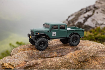 Axial 1/24 SCX24 Power Wagon crawler green truck on a rocky surface with a mountainous background